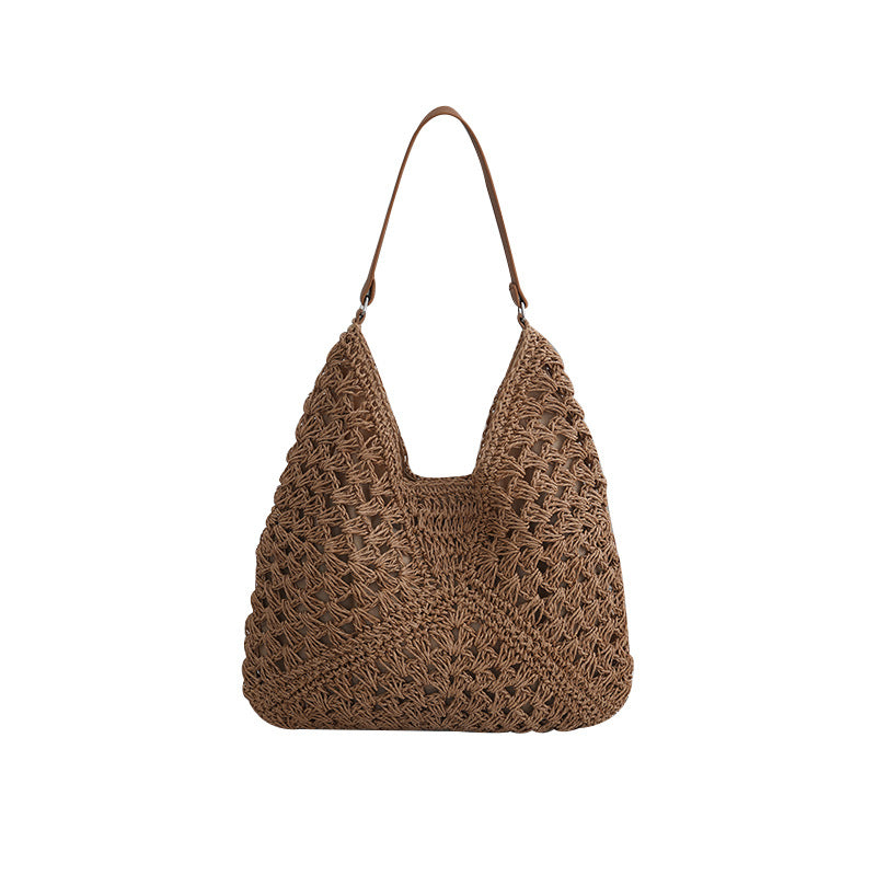 Off white hollow out straw woven bag with single woven belt strap and magnetic buckle closure in a vertical square shape.